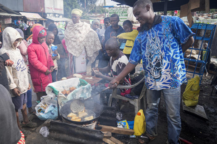 A man uses cooking oil to fry Mandazi, a type of fried bread, on a street in the low-income Kibera neighborhood of Nairobi, Kenya, Wednesday, April 20, 2022.