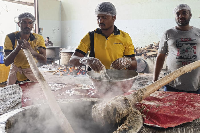 Workers pound the steaming mixture of meat, lentils, wheat and spices with long wooden paddles to give the haleem its signature smooth texture.