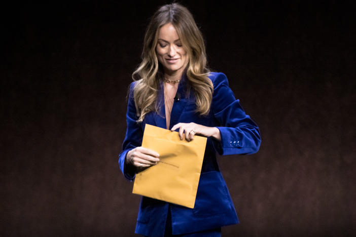 Director and actress Olivia Wilde examines an envelope reading "Personal and Confidential" while onstage during the CinemaCon convention in Las Vegas on April 26. A woman from the audience had slid the mysterious envelope toward her. It turns out she had been served with legal documents in an atypically public way.