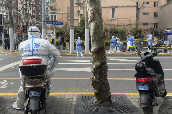 A police officer watches over residents lining up for COVID tests Shanghai.