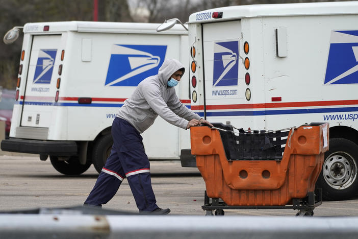 A U.S. Postal Service employee works outside a post office in Wheeling, Ill., on Dec. 3, 2021.