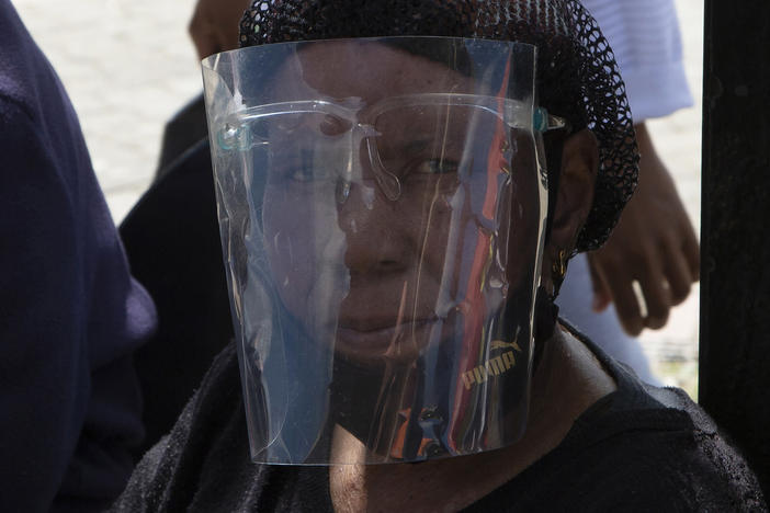 A woman wears a face shield to protect against COVID-19 at a taxi stand in Soweto, South Africa, where an omicron variant is causing a COVID-19 surge.