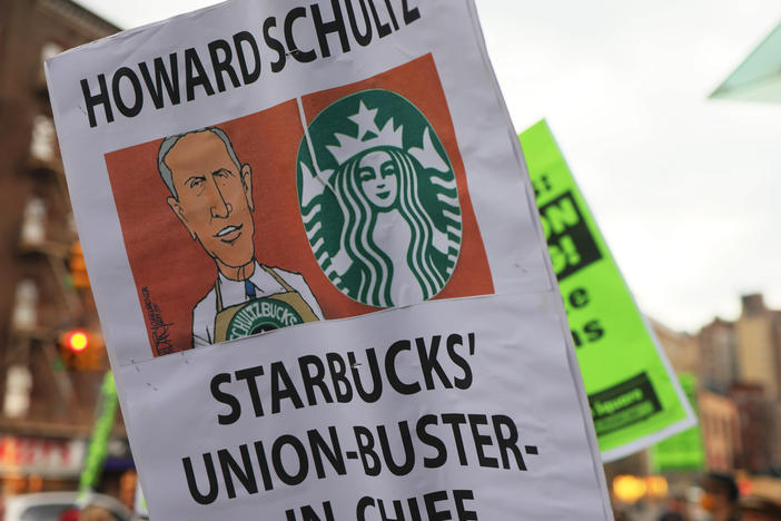 People hold signs while protesting in front of Starbucks on April 14, 2022 in New York City. Activists gathered to protest Starbucks' CEO Howard Schultz anti-unionization efforts and demand the reinstatement of workers fired for trying to unionize.