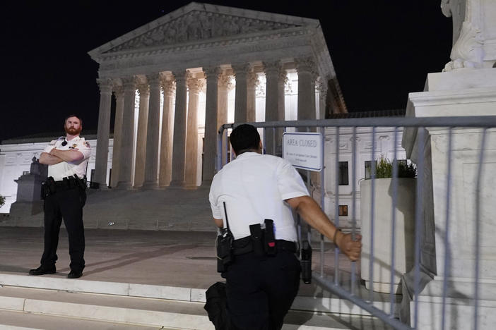 Police move barricades in place as a crowd of people gather outside the Supreme Court, Monday night, May 2, 2022 in Washington.