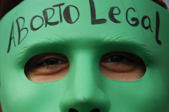 An abortion-rights activist wears a mask with text that reads in Spanish "Legal Abortion" during a rally outside Congress as lawmakers debate a bill that would legalize abortion, in Buenos Aires, Argentina, Tuesday, Dec. 29, 2020.