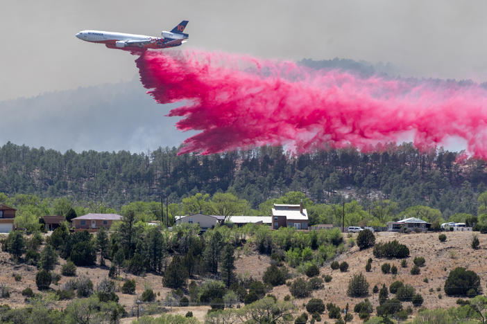 A slurry bomber dumps the fire retardant between the Calf Canyon/Hermit Peak Fire and homes on the westside of Las Vegas, N.M., Tuesday, May 3, 2022.