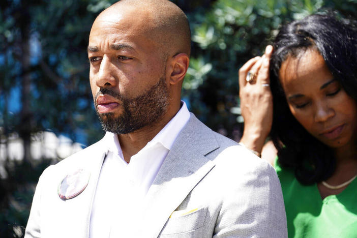 Charles Johnson wears a button with a picture of his wife, Kira, during a press conference announcing a lawsuit outside Cedars-Sinai Medical Center, Wednesday in Los Angeles. Kira Johnson died at the hospital in 2016 from complications after giving birth by cesarean section.