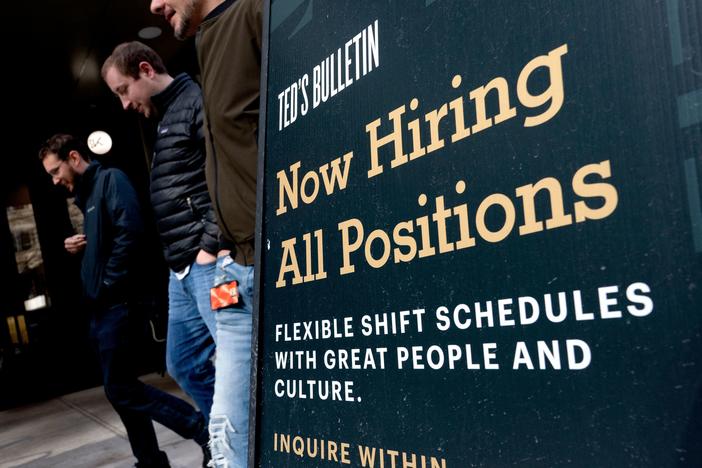 Pedestrians walk past a Now Hiring sign in Arlington, Va., on March 16.