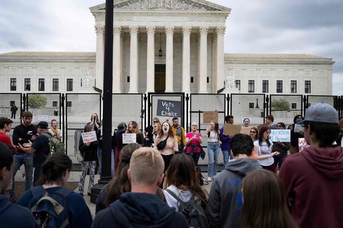 A line of anti-abortion demonstrators watch as abortion rights demonstrators chant in front of an unscalable fence that stands around the U.S. Supreme Court in Washington, D.C., on Thursday.