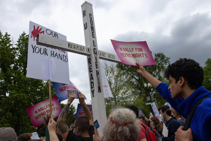 A counter-protestor holds a large cross during a youth pro-abortion rights rally outside of the Supreme Court in Washington, D.C., on May 5, following the leak of a draft Supreme Court opinion to overturn <em>Roe v. Wade</em>.