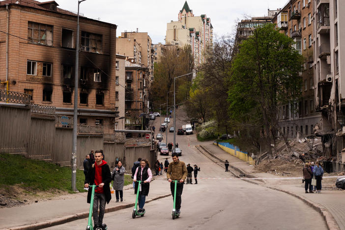 People ride scooters in Kyiv past buildings that were damaged by Russian a missile strike last week.