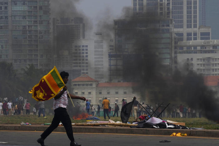 A Sri Lankan government supporter carries a national flag after attacking the anti-government demonstrators outside the president's office in Colombo, Sri Lanka, on Monday.