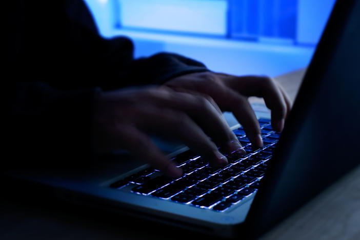 A computer programmer prints a code on a laptop keyboard.