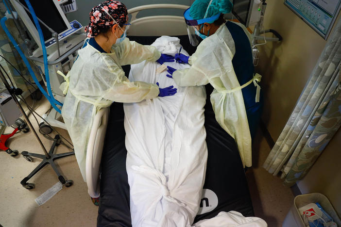 Nurse educator Katie Demelis and nurse manager Nydia White wrap the the body of a patient who died of COVID-19 at Mount Sinai South Nassau hospital in Oceanside, N.Y., on April 15, 2020.