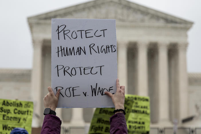 An abortion-rights protester holds up a sign during a demonstration in front of the Supreme Court on Saturday in Washington, D.C. Less than a week since the leaked draft of the Court's potential decision to overturn <em>Roe v. Wade,</em> protesters on both sides of the abortion debate continue to demonstrate in front of the building which has been fortified by a temporary fence.