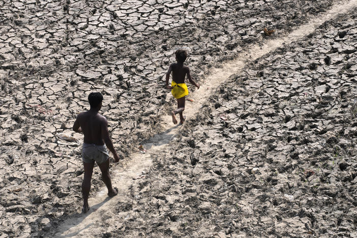 A man and a boy walk across the almost dried up bed of river Yamuna following hot weather in New Delhi, India, May 2, 2022.