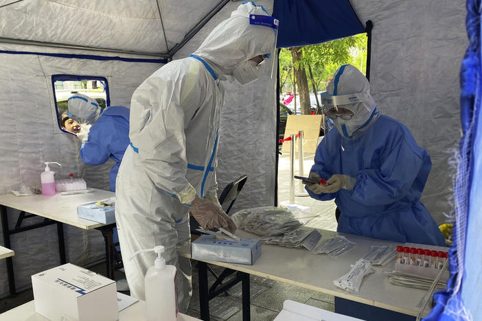 Workers in protective overalls conduct mass COVID testing for residents on May 11, 2022, in Beijing.