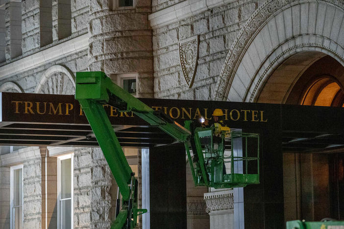 A worker removes the signage for the Trump International Hotel on Wednesday, in Washington.