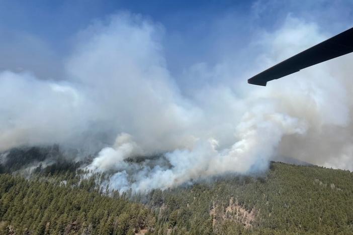 In this photo provided by the New Mexico National Guard, a New Mexico National Guard Aviation UH-60 Black Hawk flies as part of firefighting efforts, dropping thousands of gallons of water with Bambi buckets from the air on the Calf Canyon/Hermits Peak fire in northern New Mexico on Sunday, May, 1.