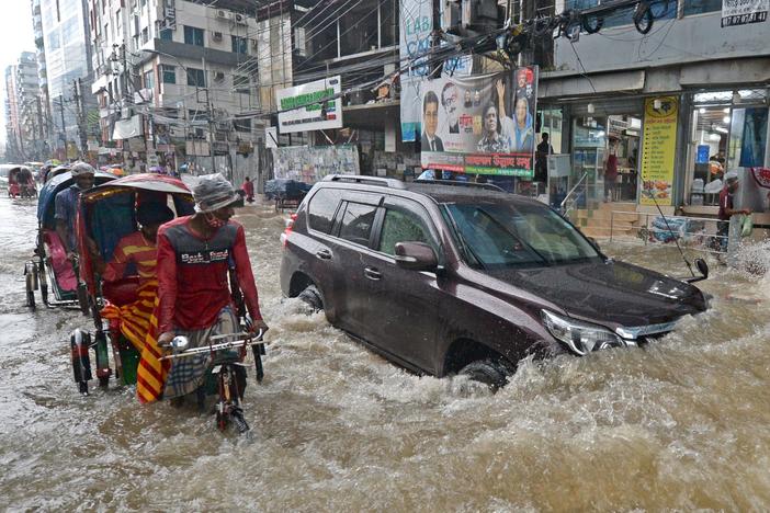 Commuters make their way through a water-logged street after a heavy downpour in Dhaka. Bangladesh is one of many countries struggling to protect residents from the effects of climate change.