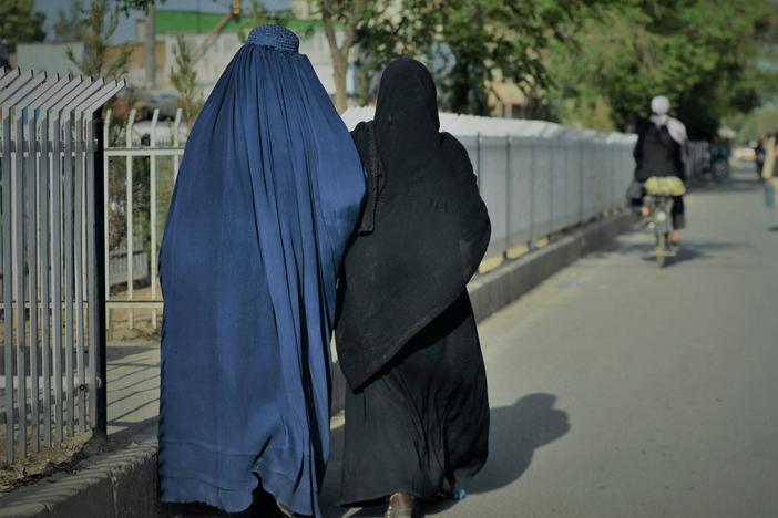 Women wearing a burqa (left) and a niqab (right) walk along a street in Kabul on May 7.