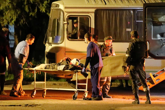 A wounded service member of the Ukrainian forces from the besieged Azovstal steel mill in Mariupol is transported out of a bus on a stretcher under escort of pro-Russian fighters, upon arrival in Novoazovsk, Ukraine, on Monday.