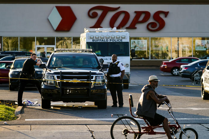 A cyclist pauses passes the scene of a shooting at a supermarket, in Buffalo, N.Y., Sunday, May 15, 2022.