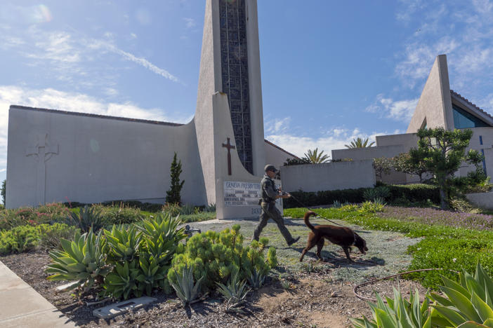 An Orange County Sheriff's Department K-9 unit checks the grounds at Geneva Presbyterian Church in Laguna Woods, Calif. on Sunday after a fatal shooting.