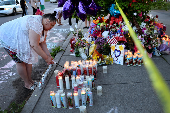 On Sunday, a woman lights a candle at a makeshift memorial to the victims of Saturday's mass shooting at Tops market in Buffalo, N.Y.
