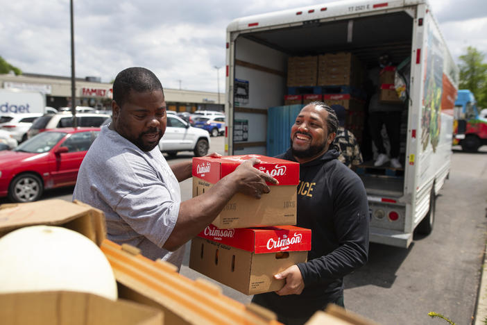 Pastor Andre Kamoche, left, and Greg Jackson, with Rehoboth House of Prayer, help unload a truck of fresh produce to be given out to people affected by the Tops closure on Tuesday in Buffalo, N.Y.