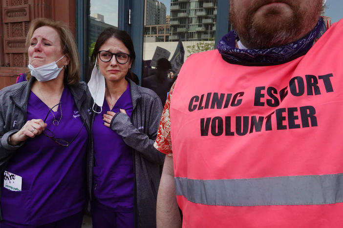 Workers at a family planning health center get emotional as thousands of abortion rights advocates march past their clinic on their way into downtown Chicago on May 14, 2022.