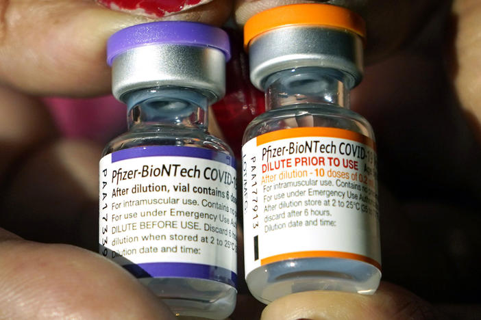 A nurse holds a vial of the Pfizer COVID-19 vaccine for children ages 5 to 11, right, and a vial of the vaccine for adults, which has a different colored label, at a vaccination station in Jackson, Miss., on Feb. 8.