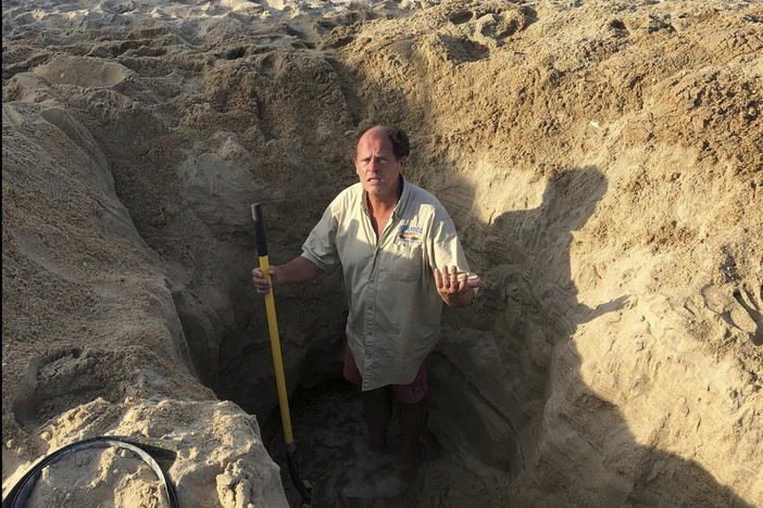 David Elder, ocean rescue supervisor for Kill Devil Hills, N.C, stands in a hole he estimates to be 7 feet deep on Sunday. The town on North Carolina's Outer Banks has issued a plea to beachgoers about the dangers of digging holes on the beach.