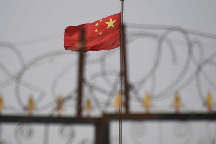 The Chinese flag is visible behind razor wire at a housing compound in Yangisar, south of Kashgar, in China's western Xinjiang region.