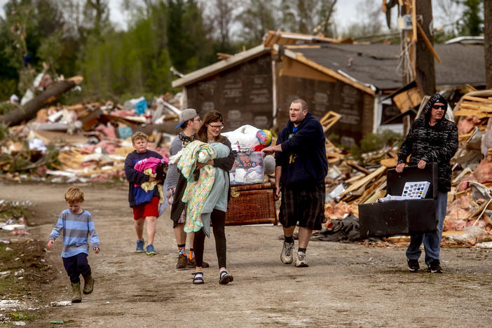 Resident Stephanie Kerwin, center, holds her baby Octavius in one arm and dog Pixie in the other as she and her family carry what they could salvage from her home in Nottingham Forest Mobile Home Park on Saturday in Gaylord, Mich., following a tornado the day before.