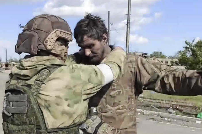 In this photo taken from video released by the Russian Defense Ministry on Friday, May 20, 2022, a Russian serviceman frisks a Ukrainian serviceman after they leaved the besieged Azovstal steel plant in Mariupol, in territory under the government of the Donetsk People's Republic, eastern Ukraine.