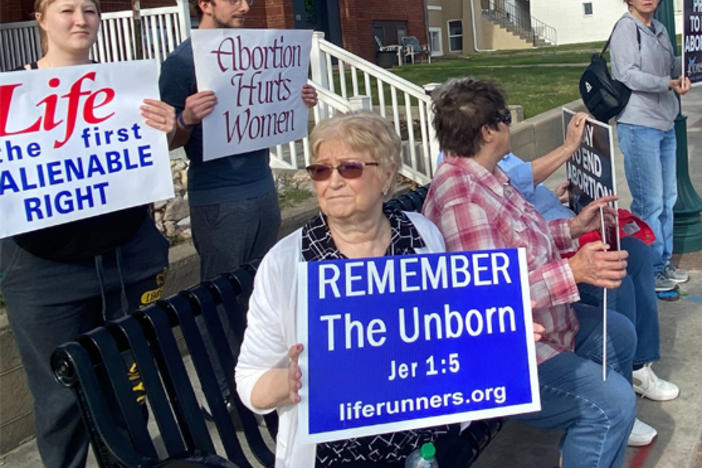 (Left) More than 100 people have been attending weekly anti-abortion prayer vigils outside the site of a future Casper, Wyo., clinic offering abortion and other health care services. (Right) Abortion-rights supporter Rikki Hayes holds up a sign near the site of a Wellspring Health Access clinic.