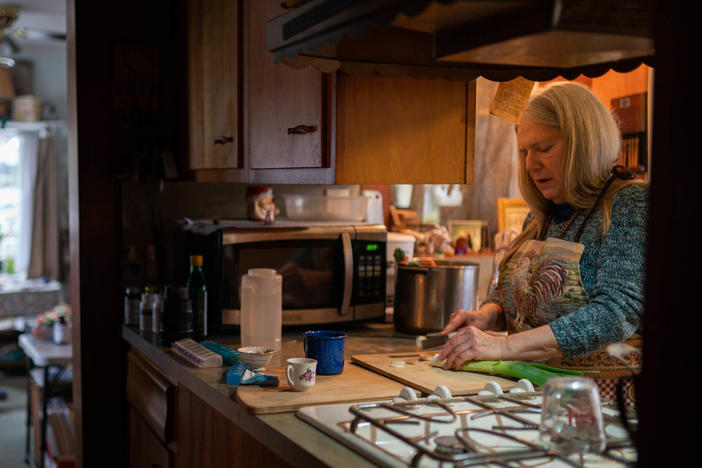 Nancy Rose, right, who contracted COVID-19 in 2021 and continues to exhibit long-haul symptoms including brain fog and fatigue, cooks for her mother, Amy Russell, left, at their home, Tuesday, Jan. 25, 2022, in Port Jefferson, N.Y. Researchers are trying to understand what causes these long COVID symptoms.