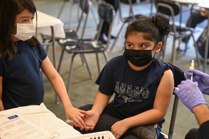 Pfizer will submit new data to the FDA this week about trials of its vaccine for kids younger than 5 years old. Here, a girl holds her sister's hand as a nurse prepares to administer the COVID-19 vaccine at a vaccination clinic in Los Angeles. Kids 5 and older have been eligible for the vaccine since last November.