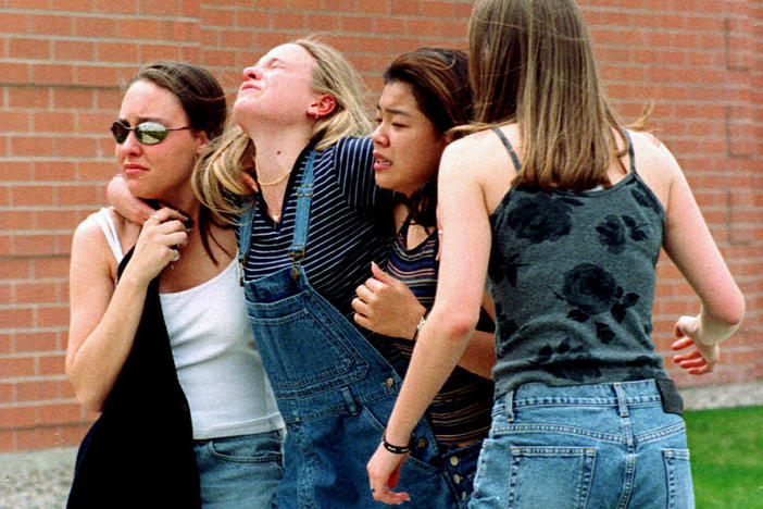 In this April 20, 1999, file photo, women head to a library near Columbine High School where students and faculty members were evacuated after two gunmen went on a shooting rampage in the school in the Denver suburb of Littleton, Colo.