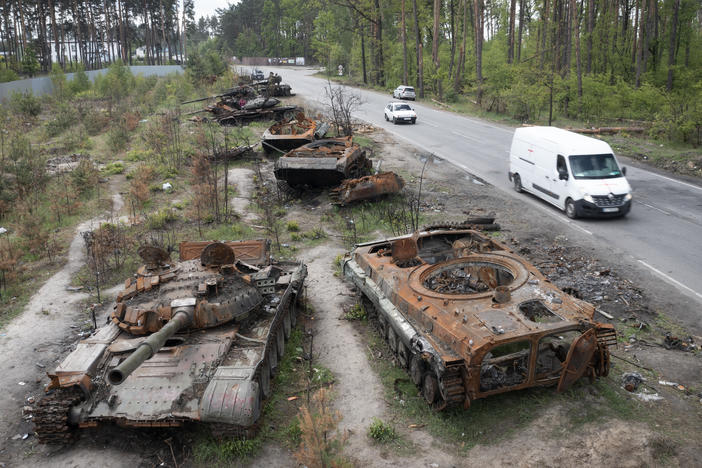 Cars pass destroyed Russian tanks from an earlier battle against Ukrainians in the village of Dmytrivka, close to Kyiv, Ukraine, on Monday. With Russian troops gone from the Kyiv region, life is returning to the city. But heavy fighting takes place daily in the east and the south of the country.