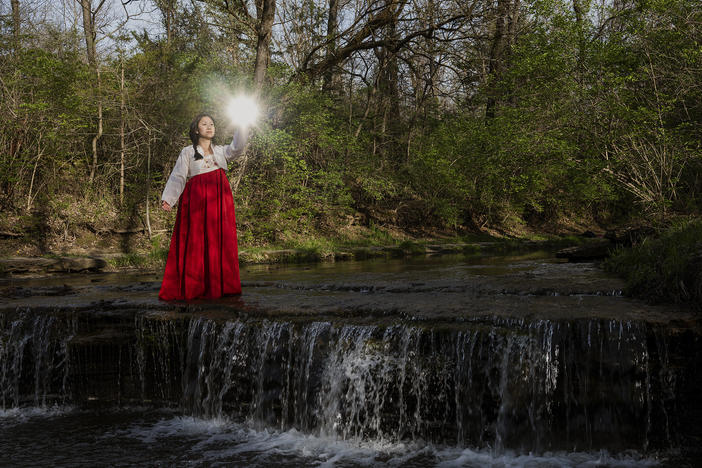 Arin Yoon recreates the scene from her mother's conception dream, holding jewels up to the light to discover the name of the child growing in her belly.