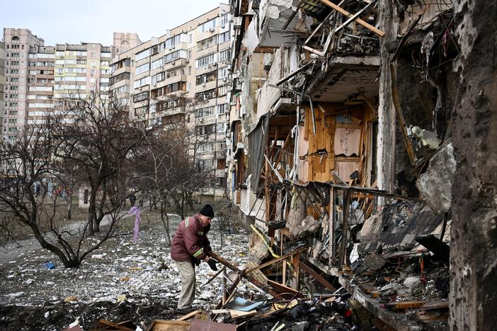A man clears debris at a damaged residential building in Kyiv in February, just after Russia started its invasion.