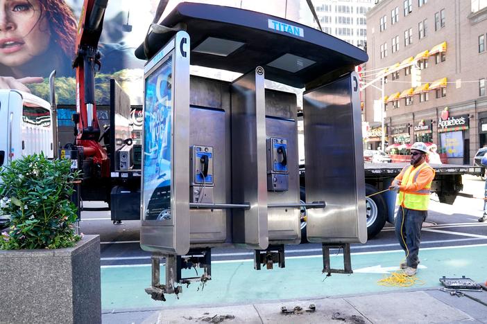 Workers remove the final New York City pay phone near Seventh Avenue and 50th Street in Midtown Manhattan on Monday. Despite the fanfare, there are still some pay phones standing in the city.