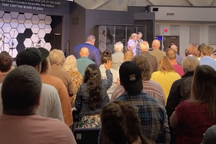 In this screenshot from a Facebook Live video of the church service by Maisey Cook, a woman takes the stage at New Life Christian Church and World Outreach in Warsaw, Ind. with her husband to tell her story of how Pastor John Lowe II had sex with her she was 16 years old.