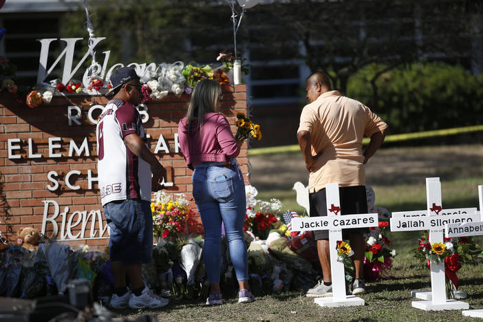 People pay their respects on Thursday at a memorial set up outside Robb Elementary School in Uvalde, Texas, the scene of the United States' most recent mass shooting. The killing of 19 children and two adults has reignited heated debates over gun control.