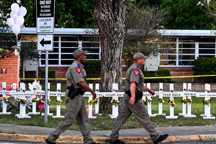 Police officers walk past a makeshift memorial for the shooting victims at Robb Elementary School in Uvalde, Texas, on Thursday.