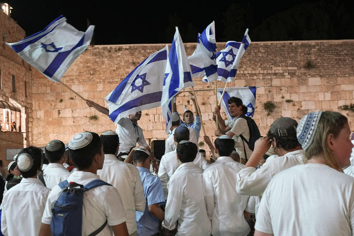 Members of Jewish youth movements dance and wave Israeli flags on the eve of Jerusalem Day an Israeli holiday celebrating the capture of the Old City during the 1967 Mideast war, next to the Western Wall, the holiest site where Jews can pray, in the Old City of Jerusalem, Saturday, May 28, 2022.