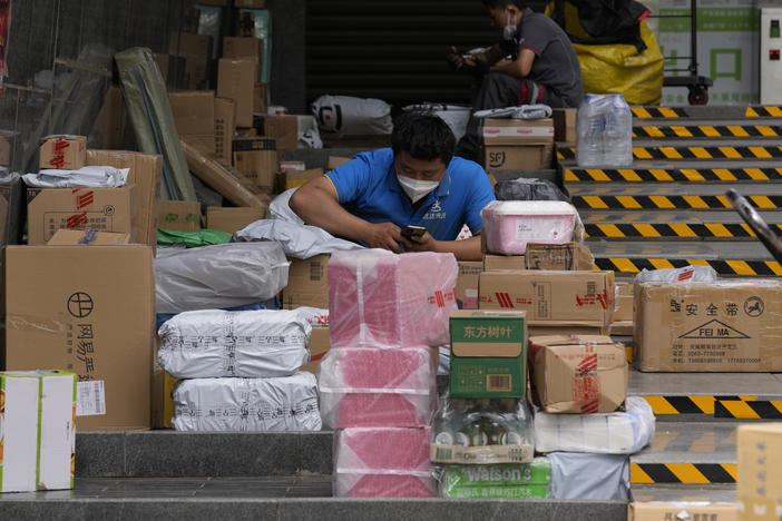 Delivery men sort out their parcels outside a community on Tuesday, May 31, 2022, in Beijing.