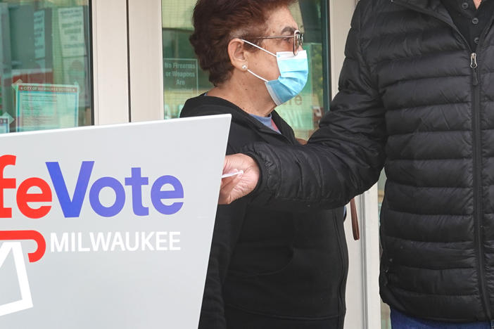 Residents drop mail-in ballots in an official ballot box outside of a Milwaukee library on Oct. 20, 2020.